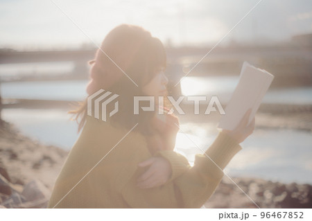 河川敷で本を読みながら佇む若い女性の写真 河川敷で本を読みながら佇む若い女性の写真 96467852