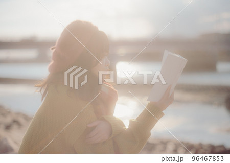 河川敷で本を読みながら佇む若い女性の写真 河川敷で本を読みながら佇む若い女性の写真 96467853
