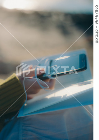 河川敷で本を読みながら佇む若い女性の写真 96467865