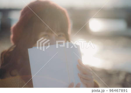 河川敷で本を読みながら佇む若い女性の写真 河川敷で本を読みながら佇む若い女性の写真 96467891