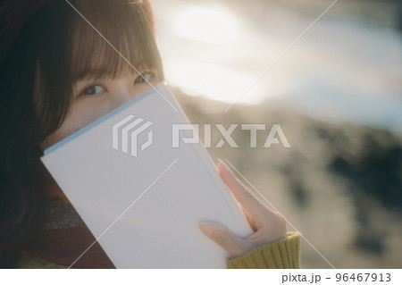 河川敷で本を読みながら佇む若い女性の写真 河川敷で本を読みながら佇む若い女性の写真 96467913