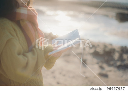 河川敷で本を読みながら佇む若い女性の写真 河川敷で本を読みながら佇む若い女性の写真 96467927