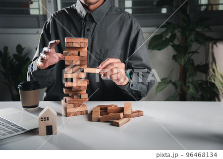 Alternative risk plan. Business hand playing tower wooden blocks game, man pull one wood block from tower he clenched his fist, show great joy in accomplishing it, Business gambling growth concept 96468134