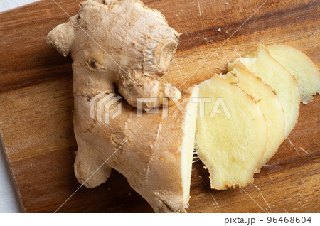 cutting fresh ginger spice at wooden desk. Healthy concept cutting fresh ginger spice at wooden desk. Healthy concept 96468604