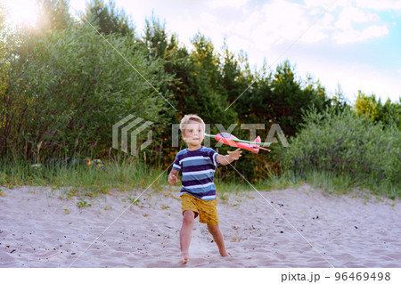 caucasian little boy launching toy plane into the air caucasian little boy launching toy plane into the air 96469498