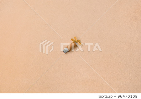 Orange usb flash memory card with a bow lies on a blanket of soft and furry light orange fleece fabric. Classic female gift design for a memory card 96470108