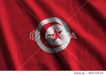 Tunisia flag with big folds waving close up under the studio light indoors. The official symbols and colors in banner 96470420
