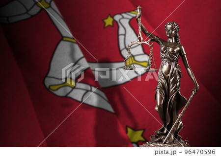 Isle of Man flag with statue of lady justice and judicial scales in dark room. Concept of judgement and punishment 96470596