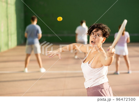 Young Argentinian woman playing pelota at open-air fronton in summer Young Argentinian woman playing pelota at open-air fronton in summer 96472500