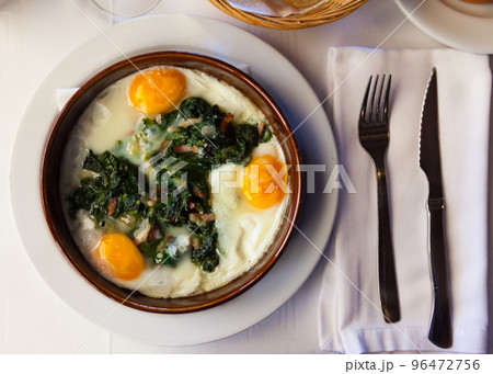 Fried eggs with spinach, raisins and ham, dish of Catalan cuisine 96472756