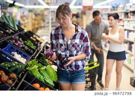 Portrait of cheerful female customer taking fresh eggplant on supermarket Portrait of cheerful female customer taking fresh eggplant on supermarket 96472798