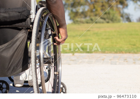 Closeup of muscular male hand touching wheelchair wheel Closeup of muscular male hand touching wheelchair wheel 96473110