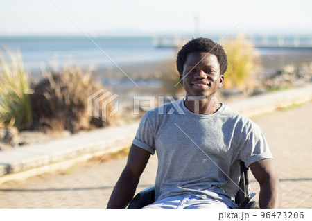 Happy Black man in wheelchair enjoying warm summer day 96473206