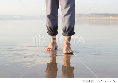 Close-up of male bare feet on wet sand Close-up of male bare feet on wet sand 96473315