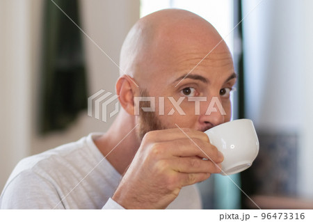 Peaceful bearded man drinking coffee at home in morning Peaceful bearded man drinking coffee at home in morning 96473316