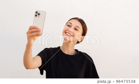 Portrait of happy young woman taking selfie with mobile phone Portrait of happy young woman taking selfie with mobile phone 96473538