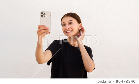 Portrait of happy young woman primping herself looking at mirror Portrait of happy young woman primping herself looking at mirror 96473540