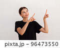 Portrait of positive young woman pointing forefingers upwards 96473550