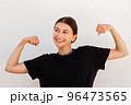 Portrait of happy young woman showing biceps 96473565