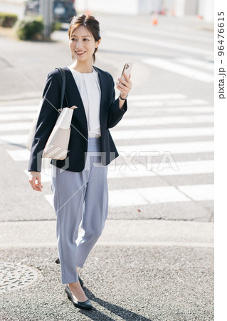 スマホを持ちながら歩く働く女性 96476615