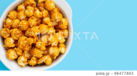 Honey caramel popcorn on blue background. Honey caramel popcorn on blue background. 96477803