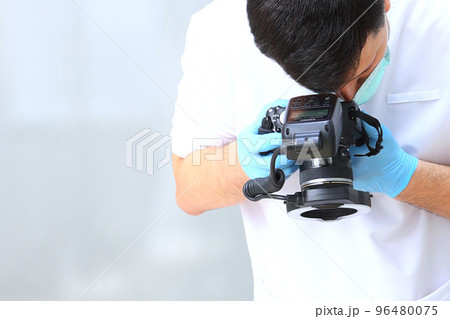 The dentist takes pictures. The camera is in the doctor's hands. Photo protocol. An unrecognizable person. Photo in the clinic. Concept of prevention and treatment of diseases. Copy space. 96480075