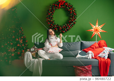 Young woman dressed in print pullover enjoying Christmas time at home 96480722