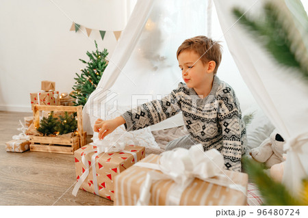 A little boy lying in a children's wigwam decorated for Christmas 96480724