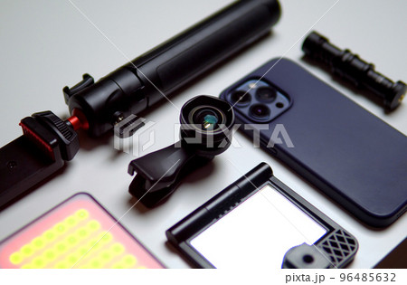 Equipment for shooting video on a smartphone. Microphone, LED lamp, tripod, lens smartphone are on a white table Equipment for shooting video on a smartphone. Microphone, LED lamp, tripod, lens smartphone are on a white table 96485632