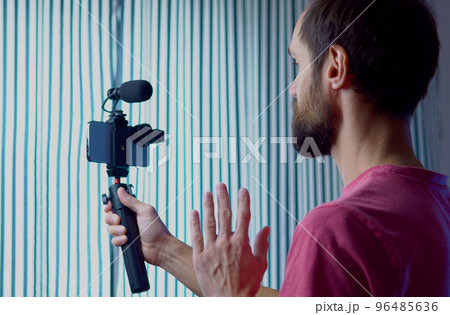 A young blogger records a video with himself on his smartphone in his room studio 96485636