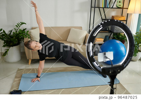 Online fitness instructor filming herself doing side plank 96487025