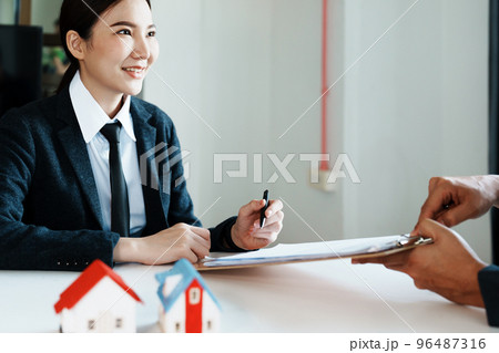 Guarantee, mortgage, agreement, contract, sign, the customer is signing the contract document as evidence to the real estate agent or bank officer according to the agreement according to the document. Guarantee, mortgage, agreement, contract, sign, the customer is signing the contract document as evidence to the real estate agent or bank officer according to the agreement according to the document. 96487316