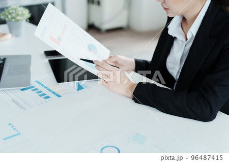 Portrait of a thoughtful Asian businesswoman looking at financial statements and making marketing documents plans on her desk. Portrait of a thoughtful Asian businesswoman looking at financial statements and making marketing documents plans on her desk. 96487415