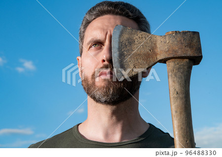 confident man cover face with axe. caucasian man hold ax. brutal man on sky background 96488330