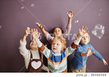 Group of cheerful cute little children catching soap bubbles 96488369
