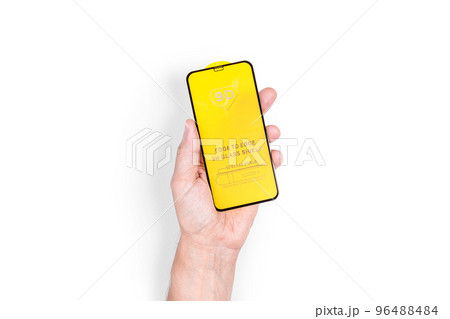 The hand holds a protective screen for a mobile phone. White background. Close-up. 96488484