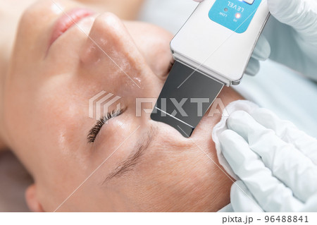 Close-up detail beautician doctor making skin care peeling cleansing procedure by ultrasonic scrubber mechanic spatula at beauty clinic salon. Specialist doing skincare treatment. Health care therapy Close-up detail beautician doctor making skin care peeling cleansing procedure by ultrasonic scrubber mechanic spatula at beauty clinic salon. Specialist doing skincare treatment. Health care therapy 96488841
