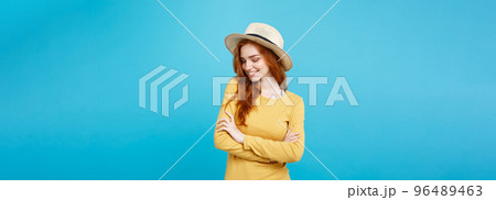 Travel concept - Close up Portrait young beautiful attractive ginger red hair girl with trendy hat and smiling. Blue Pastel Background. Copy space. Travel concept - Close up Portrait young beautiful attractive ginger red hair girl with trendy hat and smiling. Blue Pastel Background. Copy space. 96489463