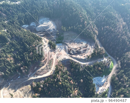 Industrial mine excavators are digging the soil in the construction site and loading trucks. Aerial drone top view. Industrial mine excavators are digging the soil in the construction site and loading trucks. Aerial drone top view. 96490487