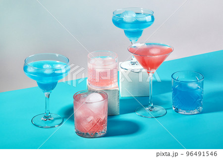 Multi-colored cocktails in glasses of different shapes on colored backgrounds with hard shadows 96491546