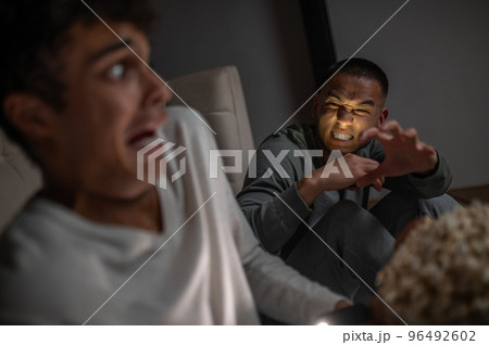 Male scaring his friend in a dark room Male scaring his friend in a dark room 96492602