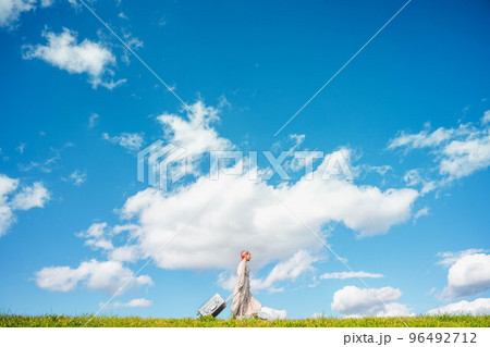 キャリーバックを持ったピンク色の髪の女性 96492712