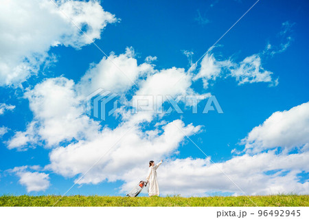 キャリーバックとたくさんの荷物を持って田舎を訪れた女性 96492945