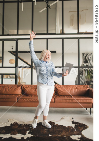 Blonde woman with a laptop feeling excited and happy Blonde woman with a laptop feeling excited and happy 96493635