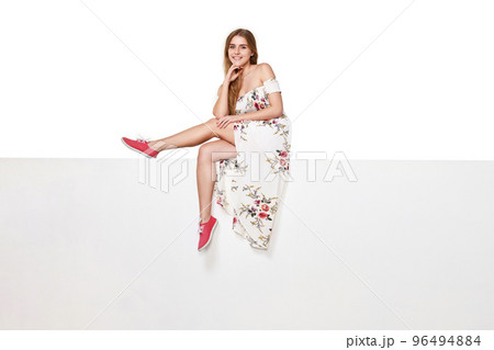 Beautiful woman in dress sitting on white banner. 96494884
