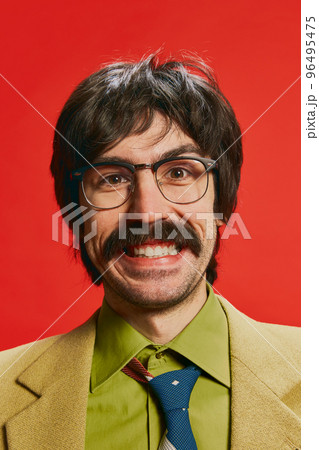 Close-up portrait of man with moustache posing in vintage suit and glasses isolated over red background. Happy 96495475