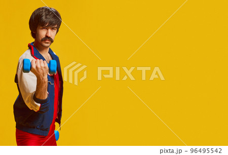 Portrait of stylish man with moustache posing in vintage sportswear training with dumbbells isolated over yellow background. Flyer Portrait of stylish man with moustache posing in vintage sportswear training with dumbbells isolated over yellow background. Flyer 96495542