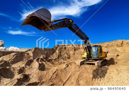 Yellow excavator working with sand at construction site 96495640
