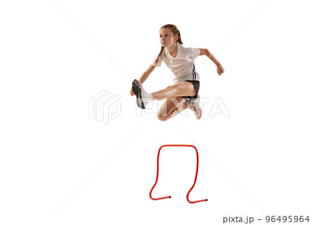 Dynamic portrait of little girl, professional athlete, runner, jogger at steeplechase training isolated over white background 96495964