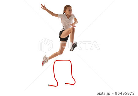 Dynamic portrait of little girl, professional athlete, runner, jogger at steeplechase training isolated over white background 96495975